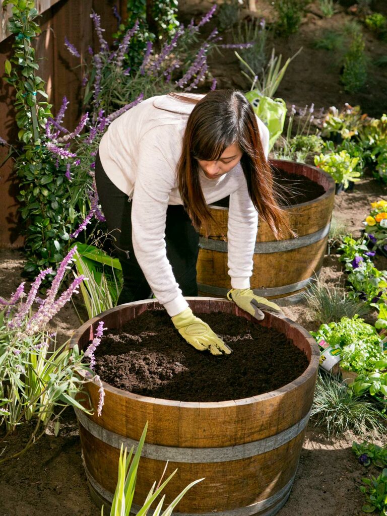 woman planting things in barrel
